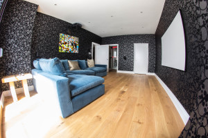 Room for watching movies on the projector. Blue sofa, wooden floor and wallpaper with skull