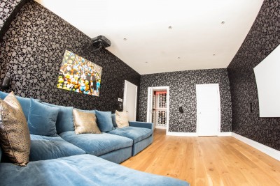 Room for watching movies on the projector. Blue sofa, wooden floor and wallpaper with skull